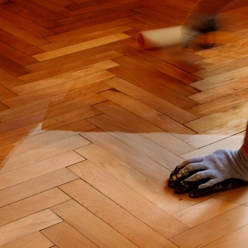applying varnish to the wooden floor.