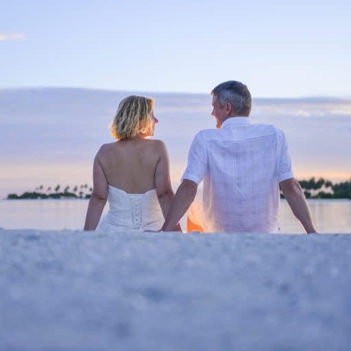 Bryllup på Maldiverne. Billede af brudeparret på stranden. Sidder i vandkanten og nyder solnedgangen
