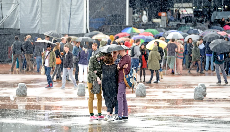 festival goers under umbrella rainy festival
