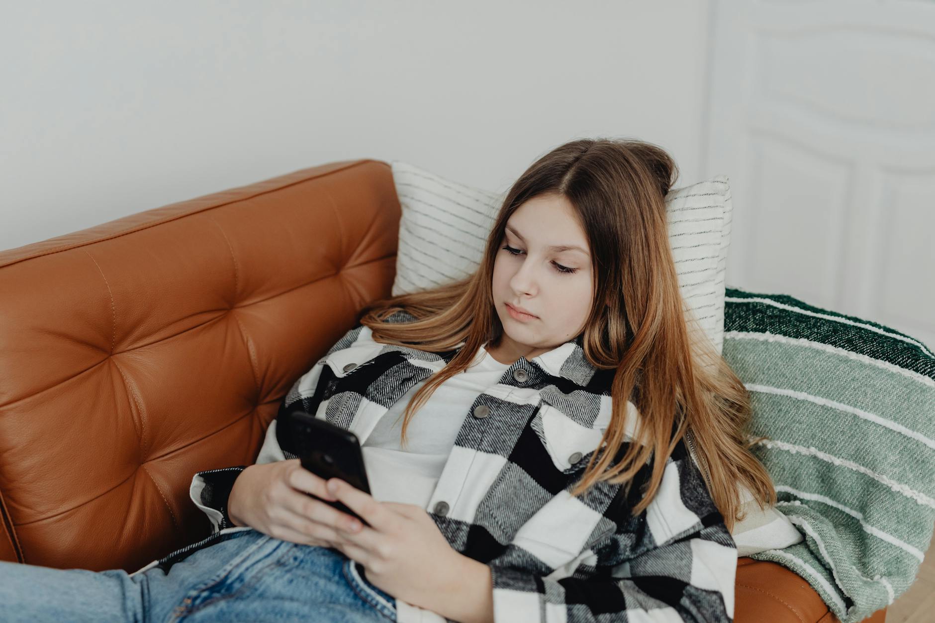 teenage girl lying on the sofa and looking at her smart phone