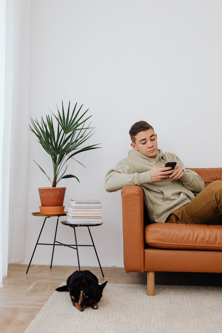 a man sitting on sofa holding a smartphone