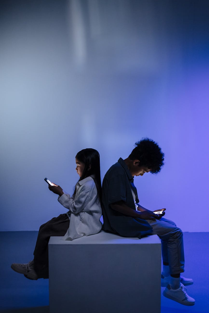 kids sitting back to back using smartphone