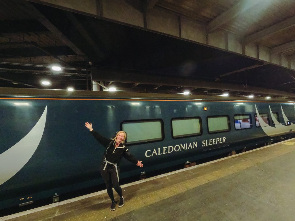 Sarah at London Euston Station, standing on the platform in front of the Caledonian Sleeper train