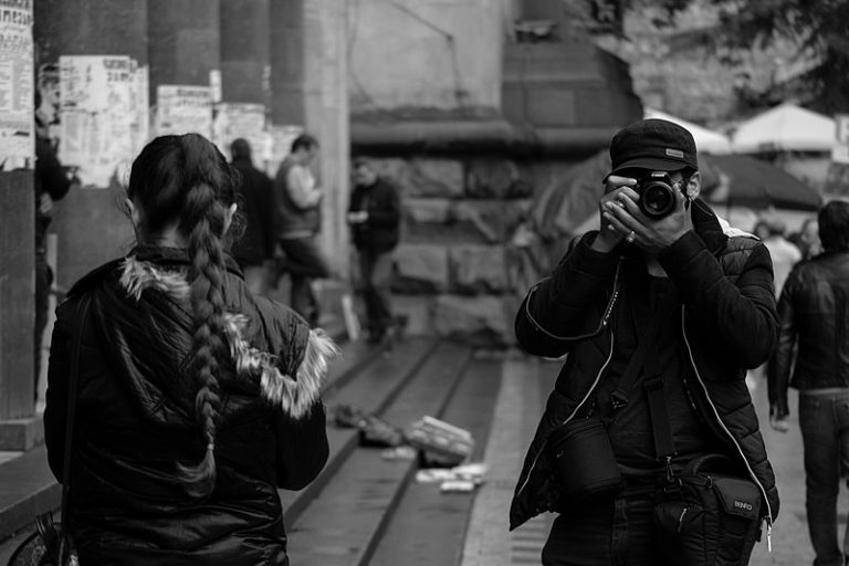 “I take photos of people taking photos. It’s my life’s work. 

I walk around the city looking for people taking photos and when they pull out their camera; I take a picture.

Every photo tells a story, and every photographer is a storyteller. My mission is to tell the story of those storytellers. 

To tear down the illusion of photography. To illuminate that there isn’t a man pointing a camera but a camera pointing at man.

It all fits in with my philosophy of mirroring people.

See, we are a reflection of people and taking a photo is the act of capturing a still of that living reflection. So when I take a photo of you taking a photo, it is the infinite meeting the infinite—an act which creates infinity.

Similar to when two dogs meet in the street.

The witnessing of oneself through the eyes of another, as oneself.  

Foreign but familiar. Different, but the same.

It’s this guiding principle that helps me meet and eventually bed young impressionable women.

See, very arty women are attracted to the nature of my work. 

They find it mysteriously deep.

Their already low self-esteem makes them feel dumb when they don’t comprehend my philosophy. Therefore, providing me with the upper-hand in our relationship. It makes them over eager to prove their worth to me.

This, coupled with the special cocktail I ply them with, paves the way for the real money shot.…which I then photograph and sell to websites as revenge porn.

Behind the lens: Photos of Photographers is the name of my work and it’s available now on Amazon.”