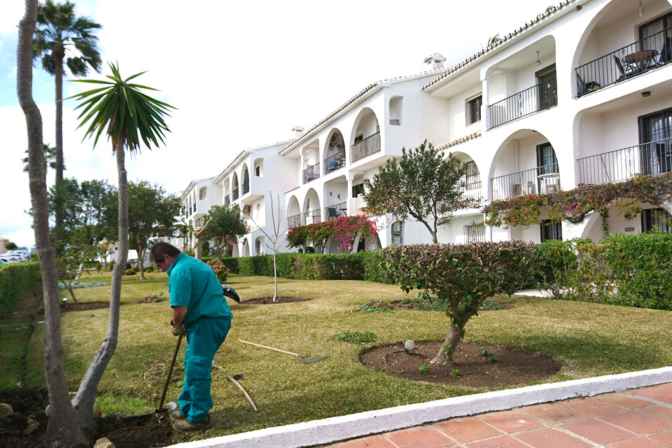 Садовник ухаживает за растениями в саду жилищного комплекса коста-дель-соль