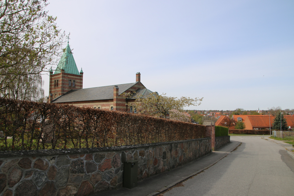 Каменная ограда с воротами и церковь Обю. В глубине видна новая церковь Обюхой. Фото 28 апр. 2023, Обюхой / Åbyhøj, Дания
