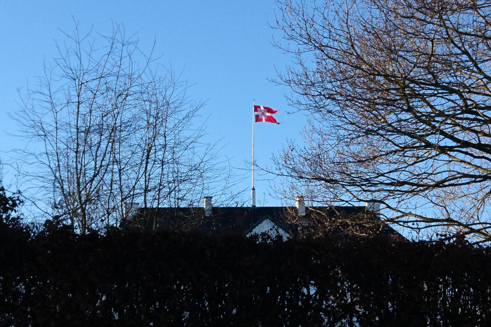 Флаг королевы над крышей дворца Марселисборг, г. Орхус, Дания. 27 дек. 2021