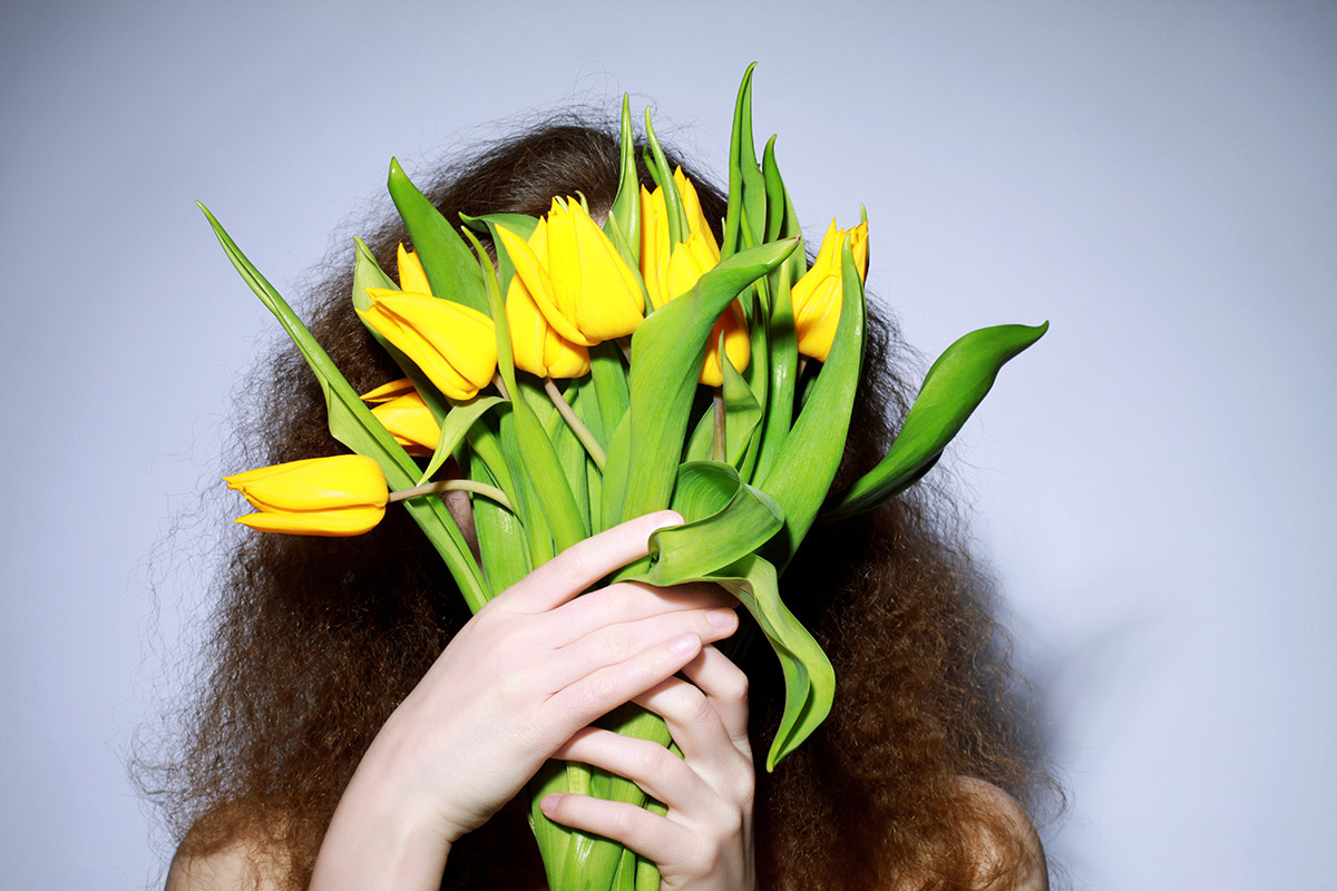 woman holding yellow flower