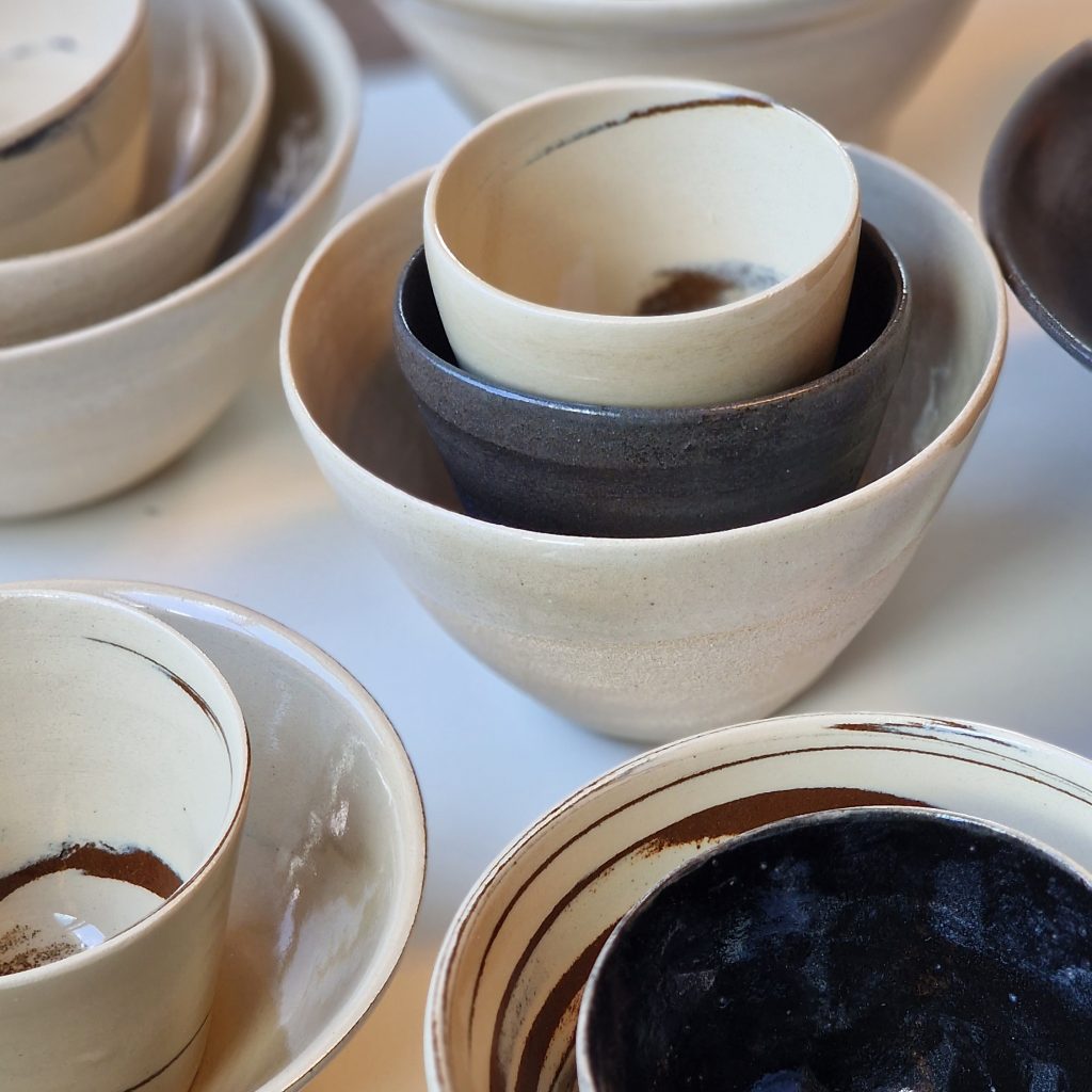 Nærbilder av beige og sorte keramikkskåler som står stablet på et hvitt bord