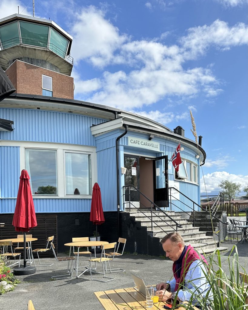 Cafe Caravelle inngangsparti blått bygg med sort dør og blå himmel i bakgrunnen