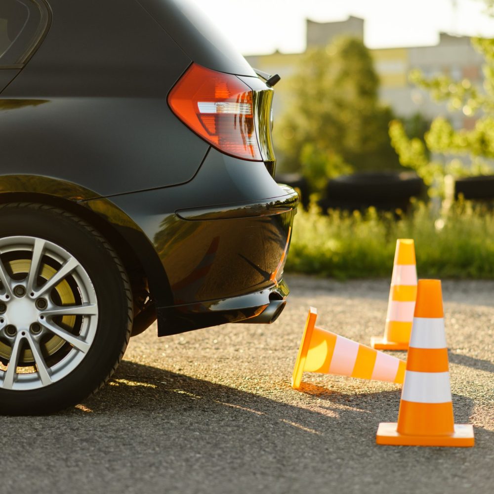 Car and orange traffic cones, lesson in driving school concept, nobody. Teaching to drive vehicle theme. Driver's license education