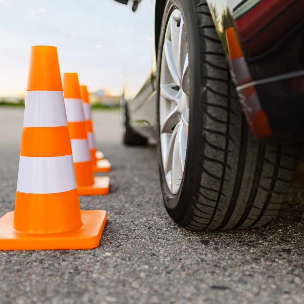 Car and orange traffic cones, lesson in driving school concept, nobody. Teaching to drive vehicle theme. Driver's license education