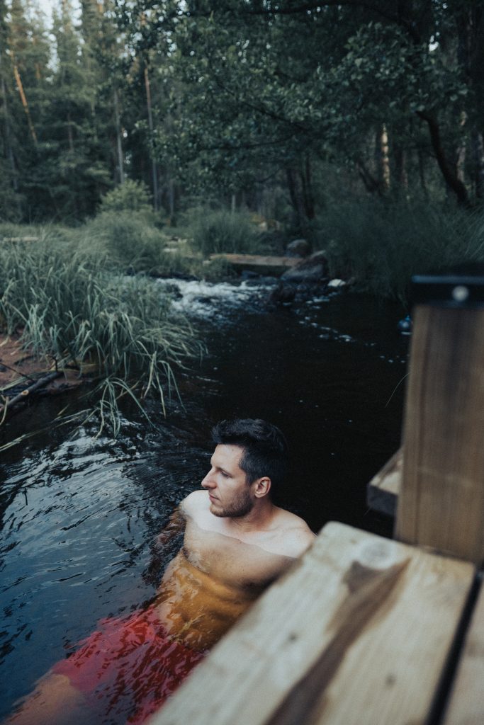 man badar i en å i skogen