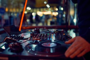 turntable, hand of dj on the vinyl record at night club. blured background