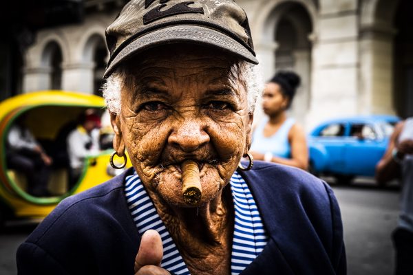 Fra gamlebyen i Havana, Cuba. En gammel dame med furet ansikt er på jakt etter noe å tenne cigaren sin med.