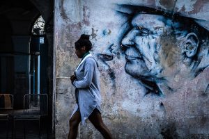 Tidlig morgen i gamlebyen i Havana, Cuba. En kvinne haster forbi en nedslitt bygård med grafitti på vei til dagens ærender.