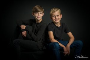 Portret van twee broers gemaakt in een fotostudio tegen een zwarte wand