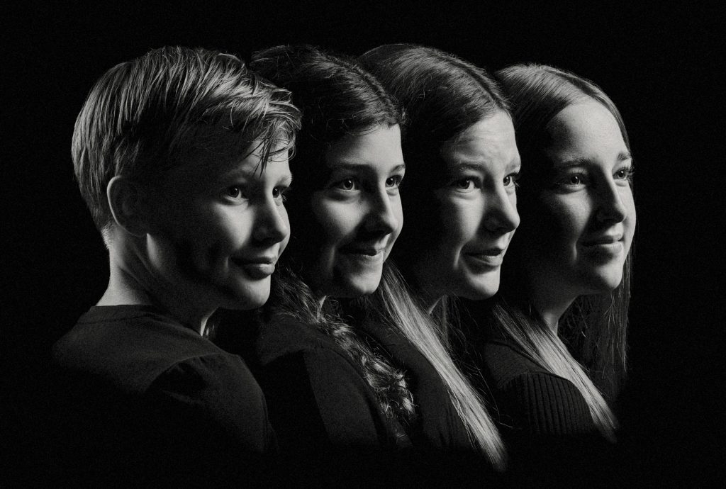 Familieportret van vier kinderen op een rij, gemaakt in Fotostudio Rotterdam. Zwartwit.