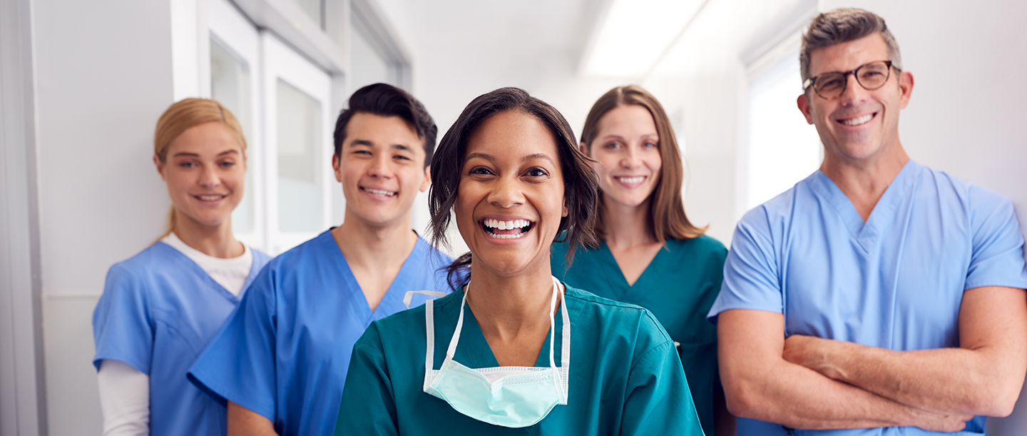 Portrait Of Laughing Multi-Cultural Medical Team Standing In Hospital Corridor