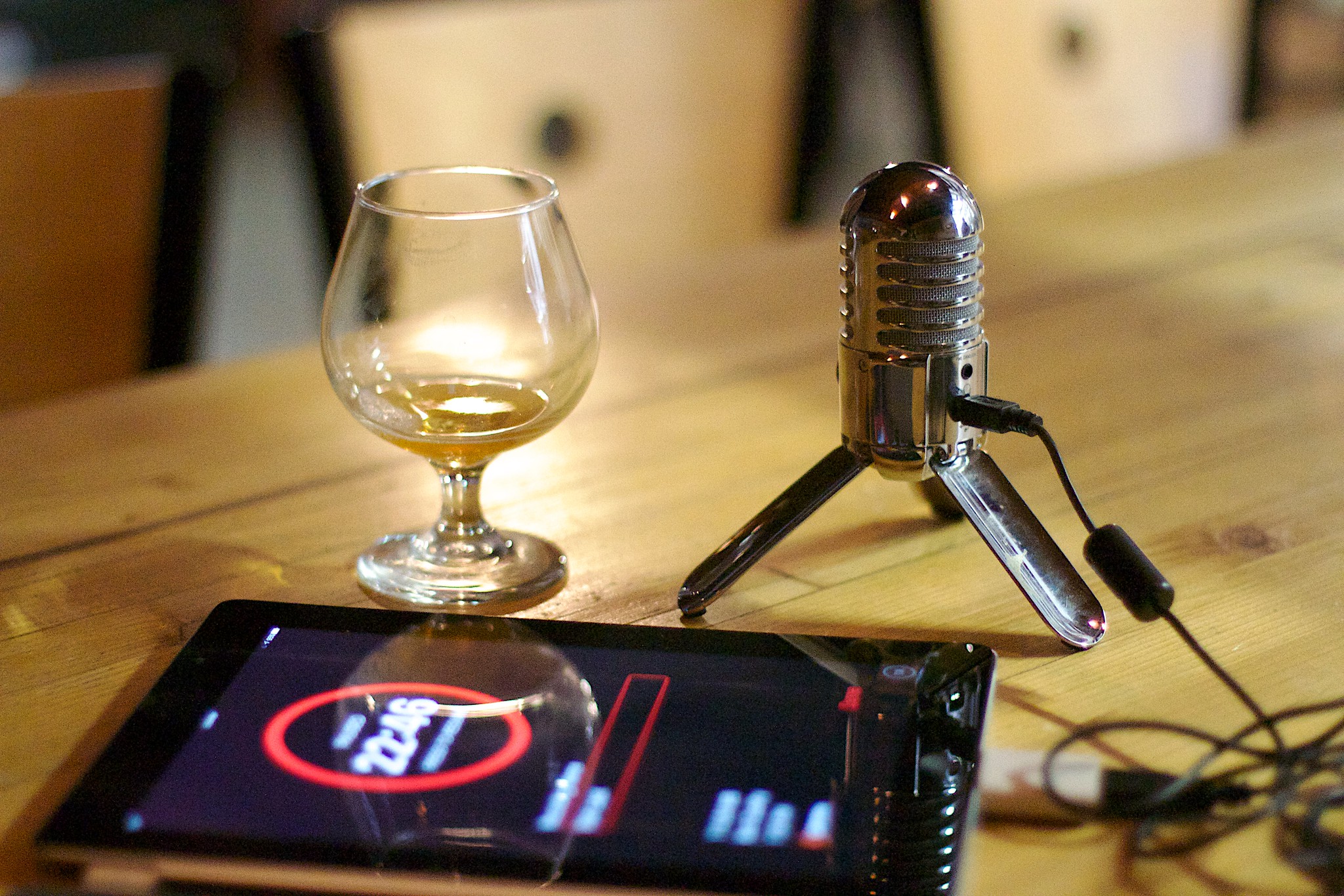 Podcast Equipment, Mikrofon, Tablet und ein Weinglas auf einem Tisch