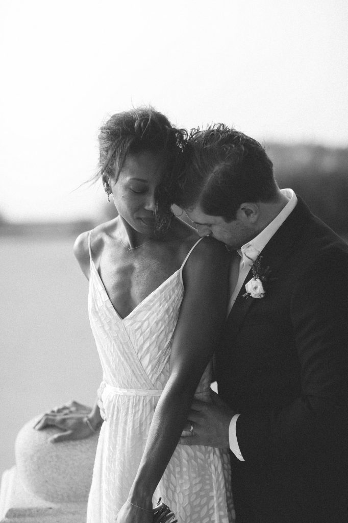 Photo mariage Belgique noir & blanc. Le marié embrasse l'épaule de la mariée par l'arrière.