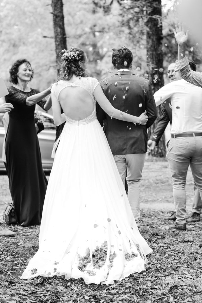 Photo mariage Belgique en noir et blanc des mariés de dos sous les pétales de fleurs