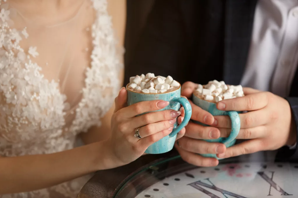 Mariés qui tiennent une tasse de chocolat chaud avec de marshmallow