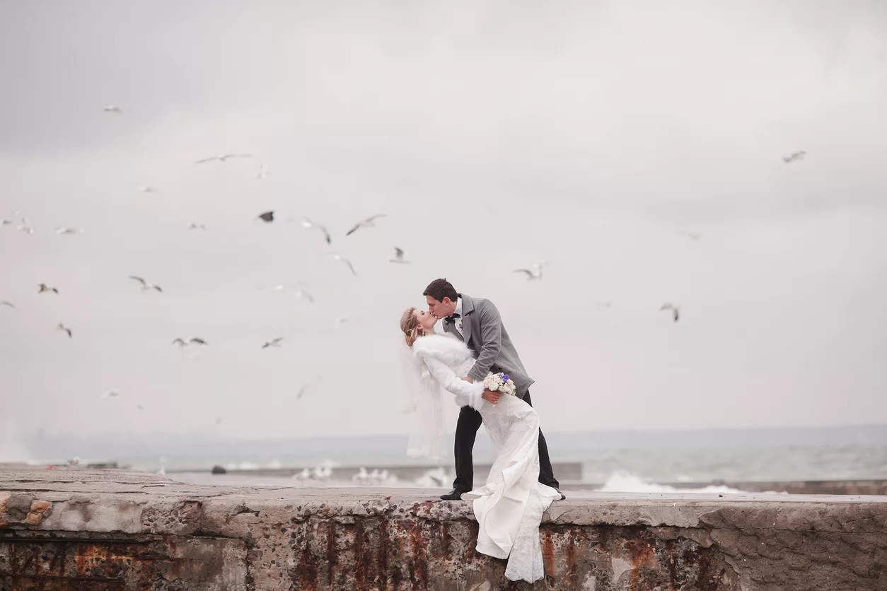 Couple de mariés qui s'embrassent sur la plage en hiver