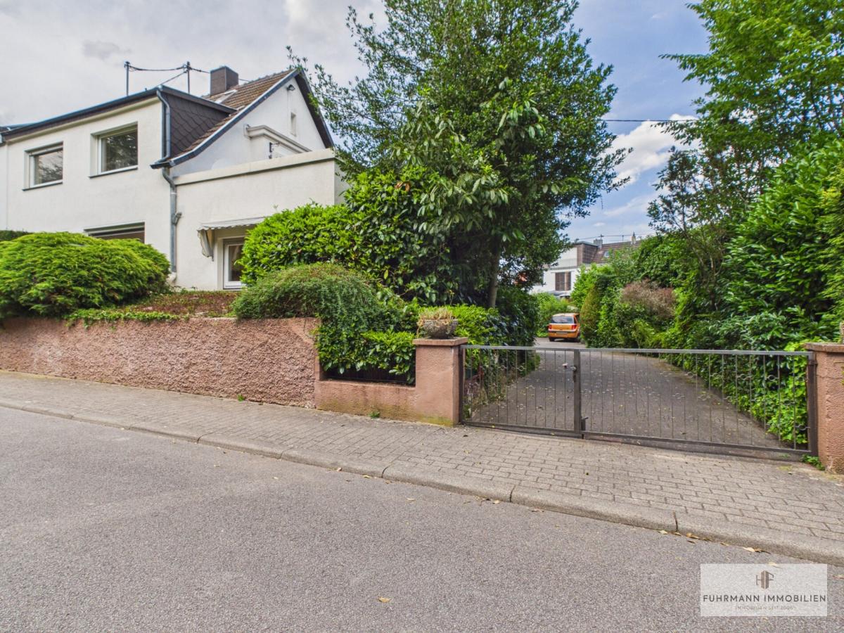 Ansicht des Grundstücks mit Zufahrt und eingewachsenem Gartenbereich