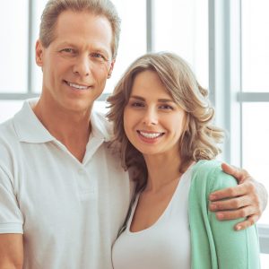 Portrait of happy beautiful couple in casual clothes cuddling, looking at camera and smiling