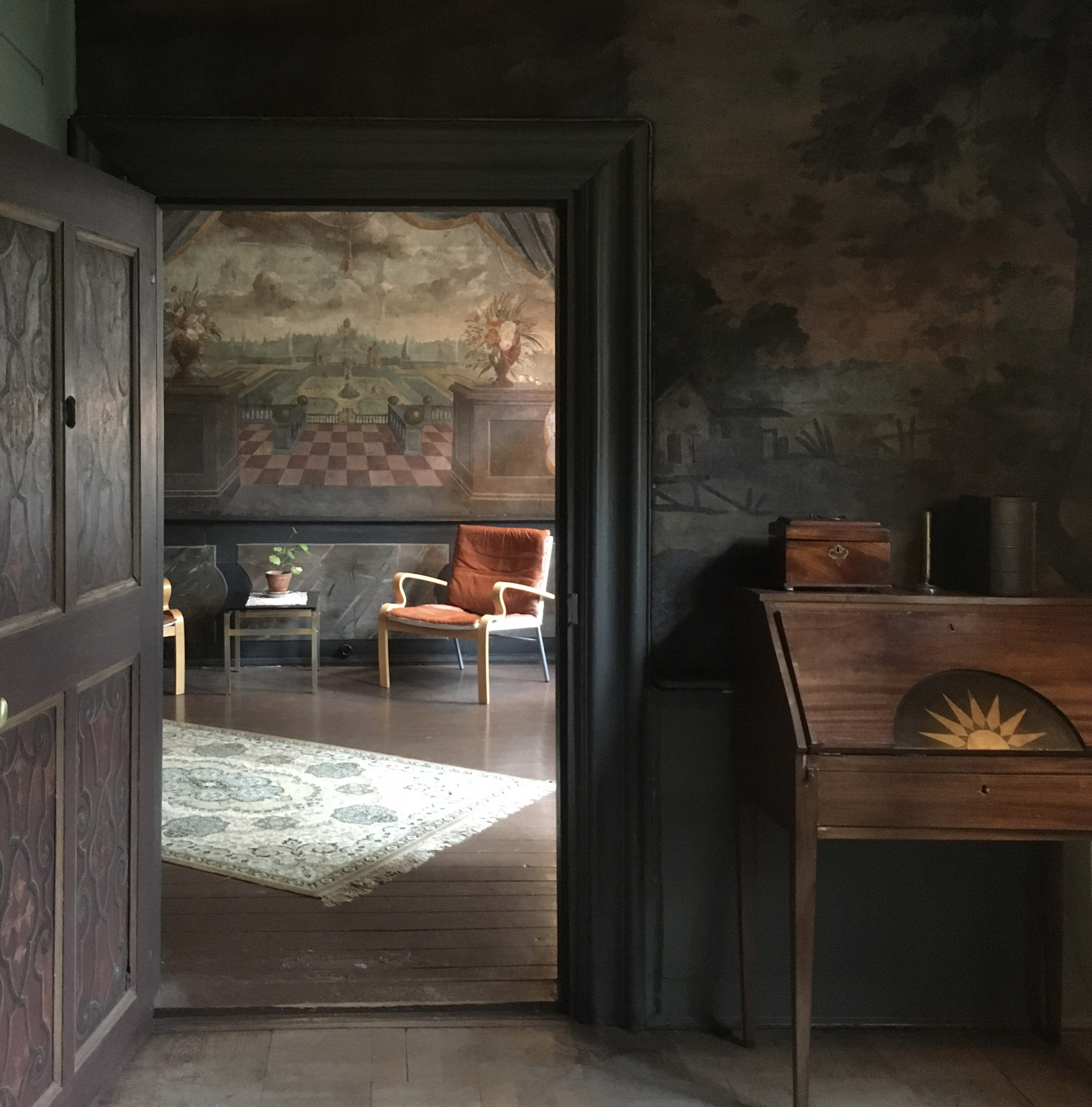 A room featuring two chairs, a cabinet, a rug and a plant