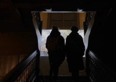 The backs of two people walking up a staircase