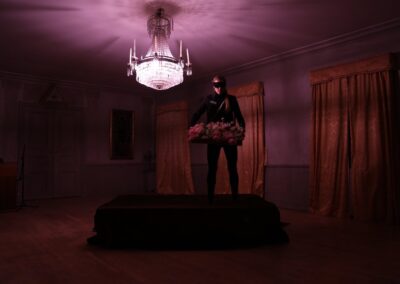 A man standing on a table, offering a plate of food in a dimly lit room