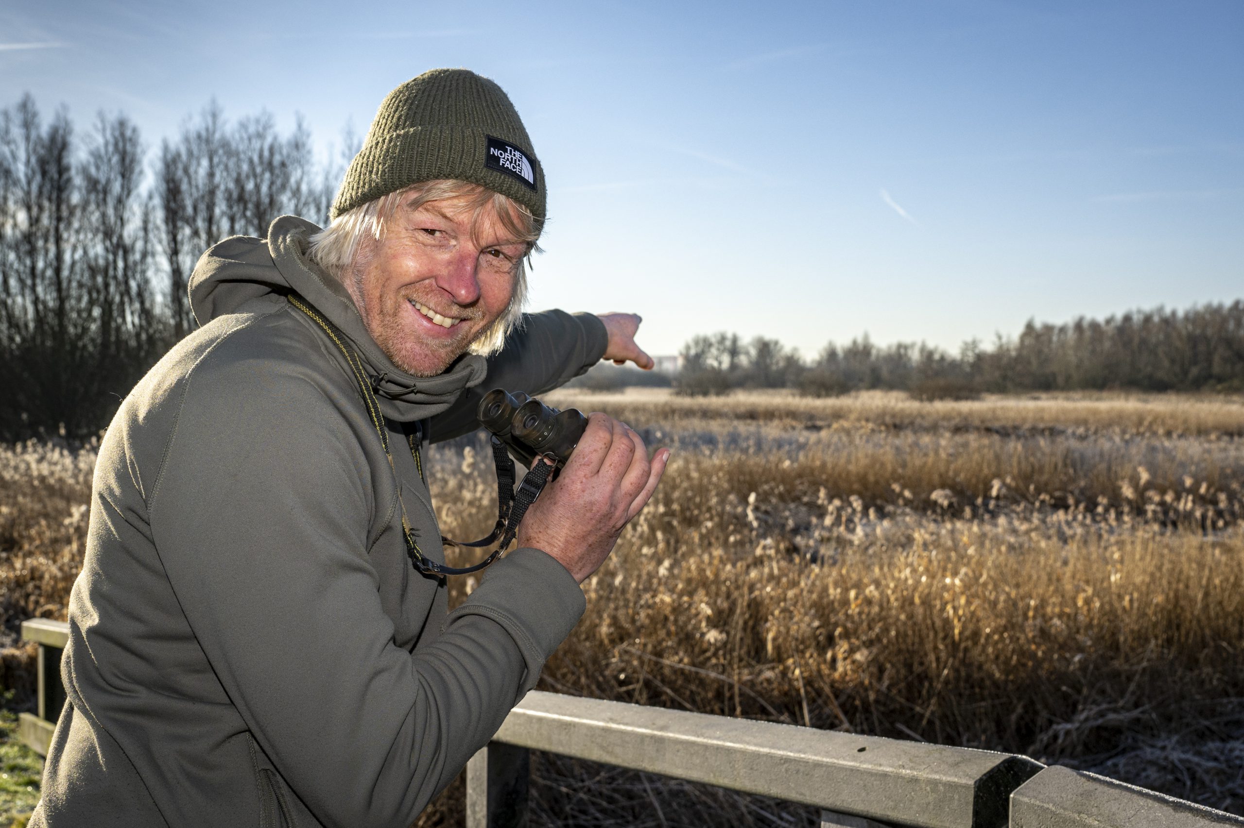 PraatmedeRaad-DavidSluis-01 Afbeelding van Ecoloog David Sluis met verrekijker die een veld in wijst.