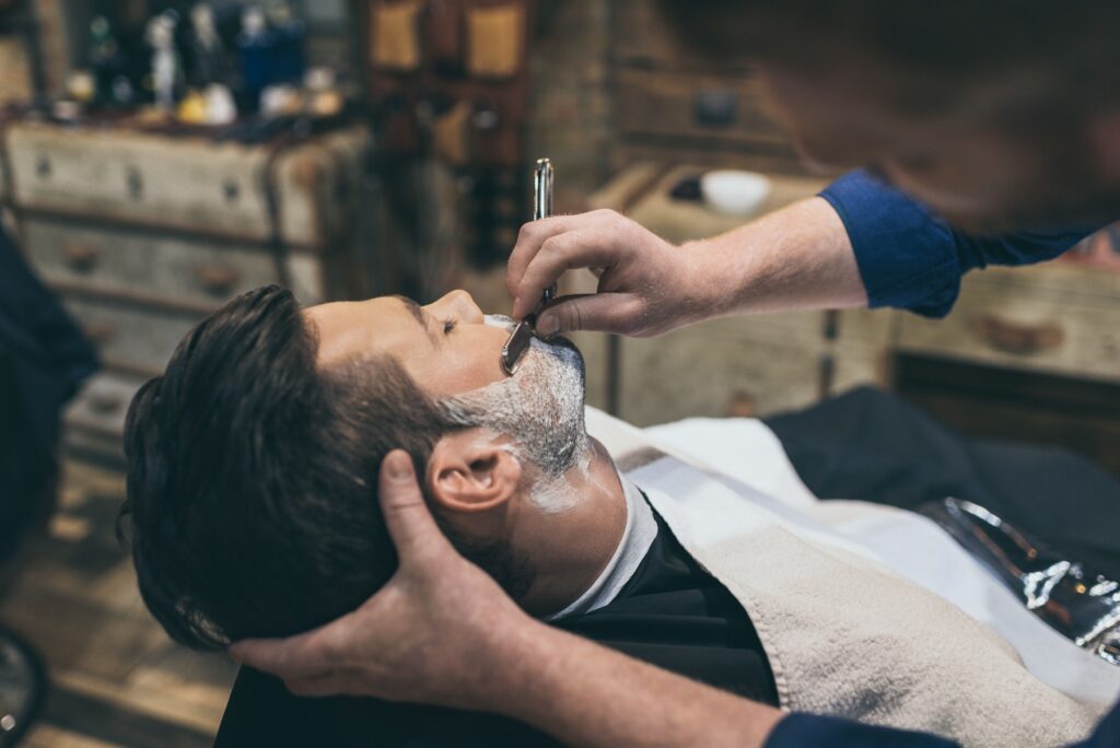 Barber shaving customers beard in vintage barber shop