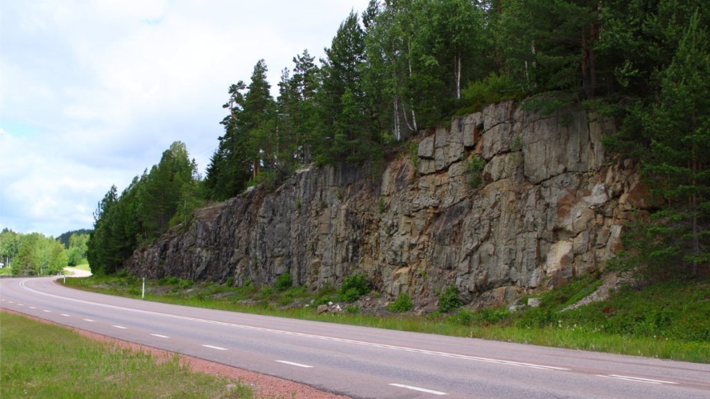 Översikt över vägskärning där man på nära håll kan se olika bergarter. Foto: Lovis Uhlgrén. 