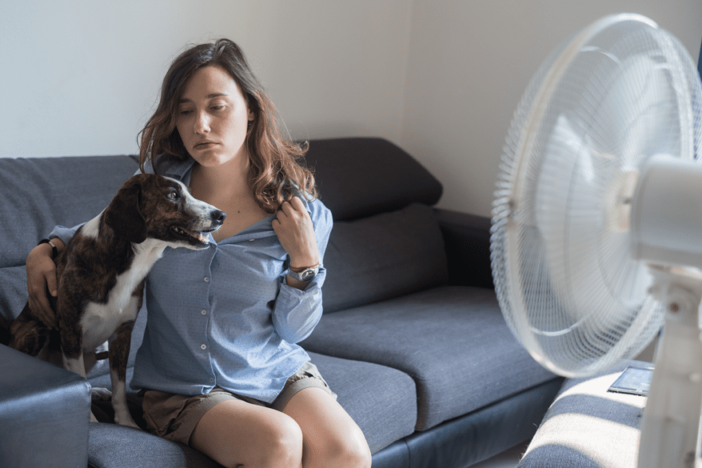 Frau mit Hund vor einem Ventilator Klimaanlage