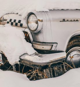 Classic automobile covered in snow, showcasing vintage style and intricate design elements.