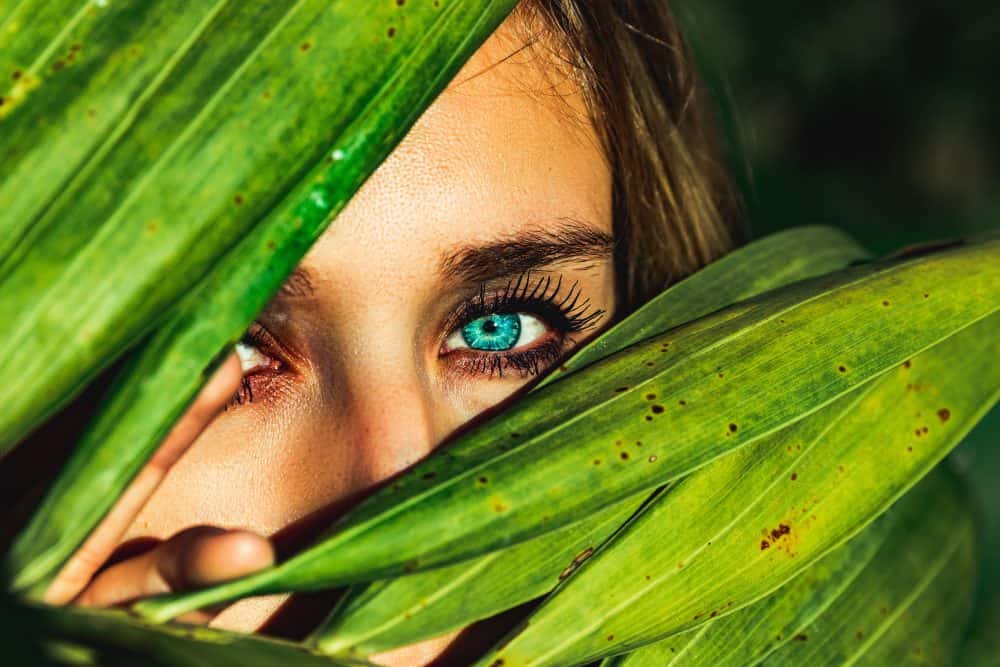 Women with green eyes looking from behind leaves