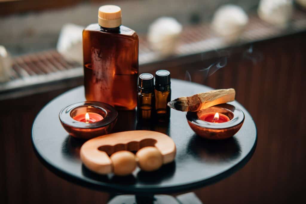 Tafel met massage-olie, etherische olie, een waxinelichtje, massageroller en palo santo