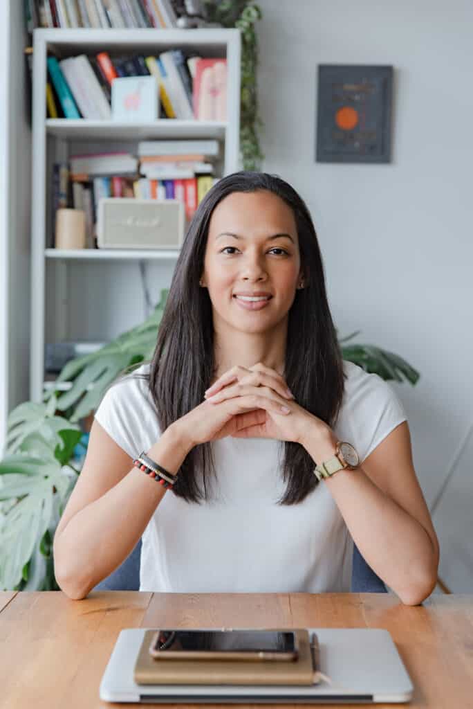 Pamela Ramnares Ayurvedisch Practitioner, yogadocente en reiki master zit aan bureau met ellebogen op tafel en handen gekruist.