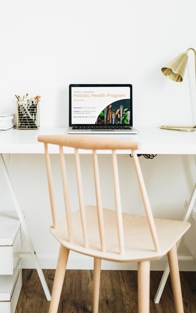 Bureau en stoel met laptop en scherm waarop een holistisch programma ayurveda van Ginger & Yoga te zien is.