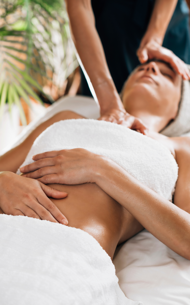 Vrouw ontvangt massage met olie en is bedekt met witte handdoeken