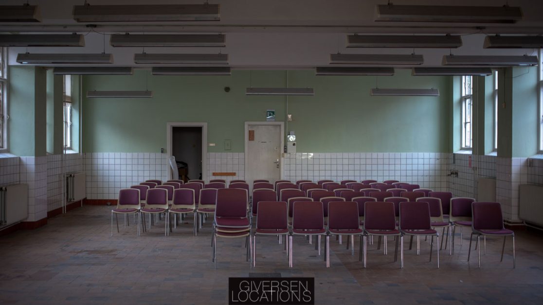 Stor sal med tomme stole på et gammelt hospital