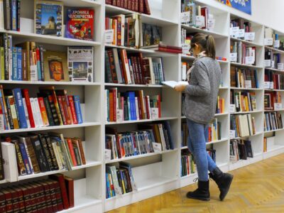 Student reading archived books from a bookshelf