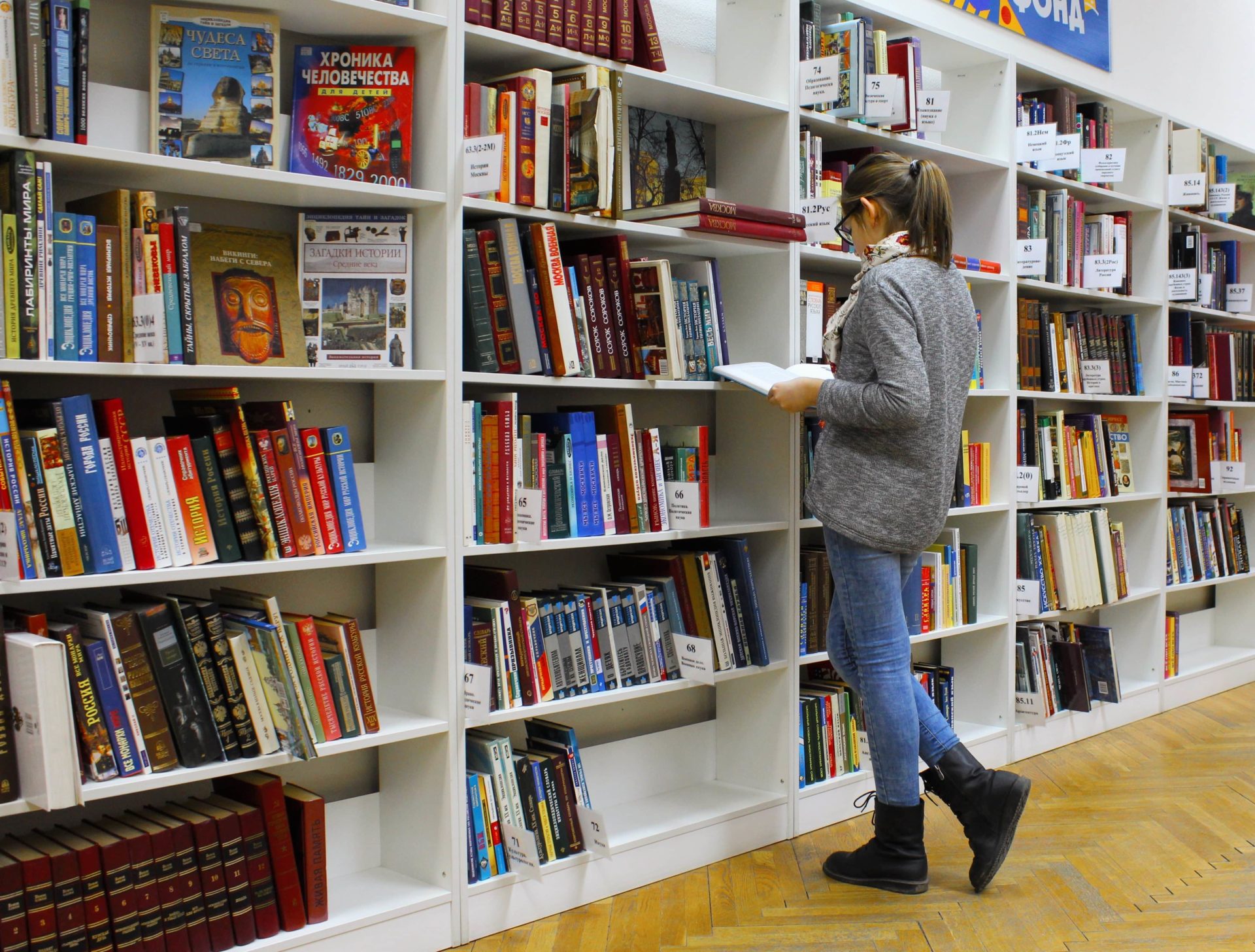 Student reading archived books from a bookshelf