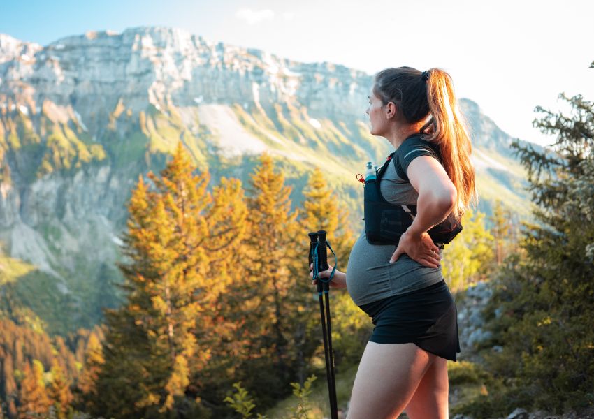 Gravid kvinde vandrer og dyrker motion i naturen