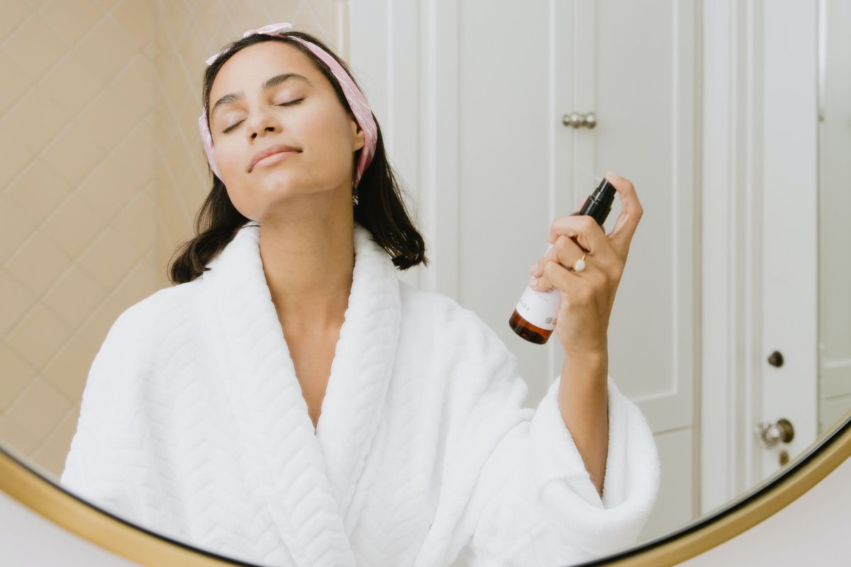 Woman applying Apple cider vinegar on her face using a spary bottle