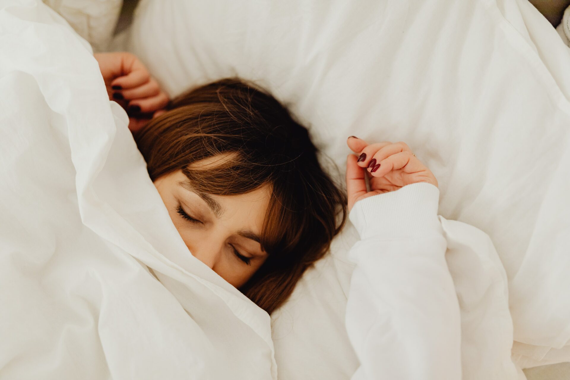 A woman under a white blanket taking a deep sleep