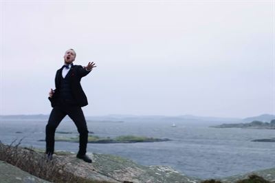 Teodor Ostwald ensam med hav och klippor i bakgrunden sjunger med kör i Göteborg